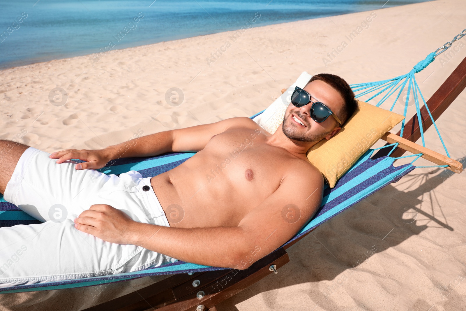 Photo of Young man relaxing in hammock on beach