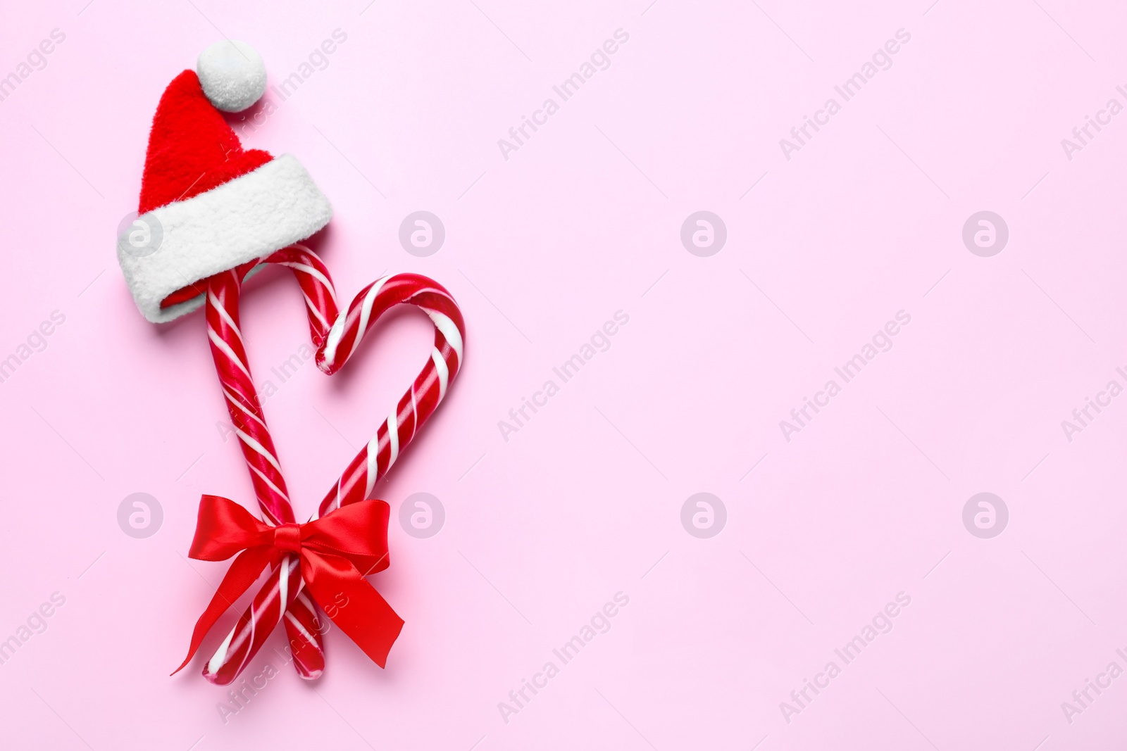 Photo of Flat lay composition with Christmas candy canes on pink background. Space for text