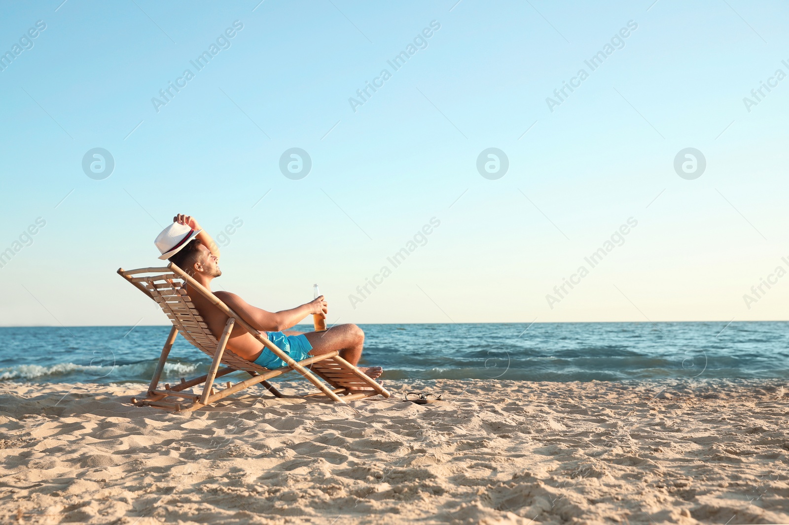 Photo of Young man relaxing in deck chair on beach near sea