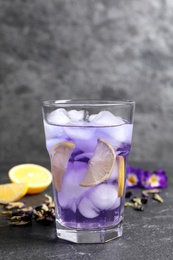Photo of Organic blue Anchan with lemon in glass on grey table. Herbal tea