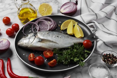 Fresh dorado fish and ingredients on white marble table