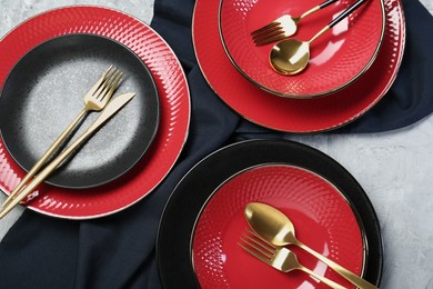 Stylish ceramic plates and cutlery on light table, flat lay