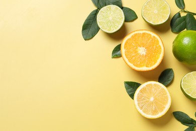 Photo of Different cut and whole citrus fruits on yellow table, flat lay. Space for text