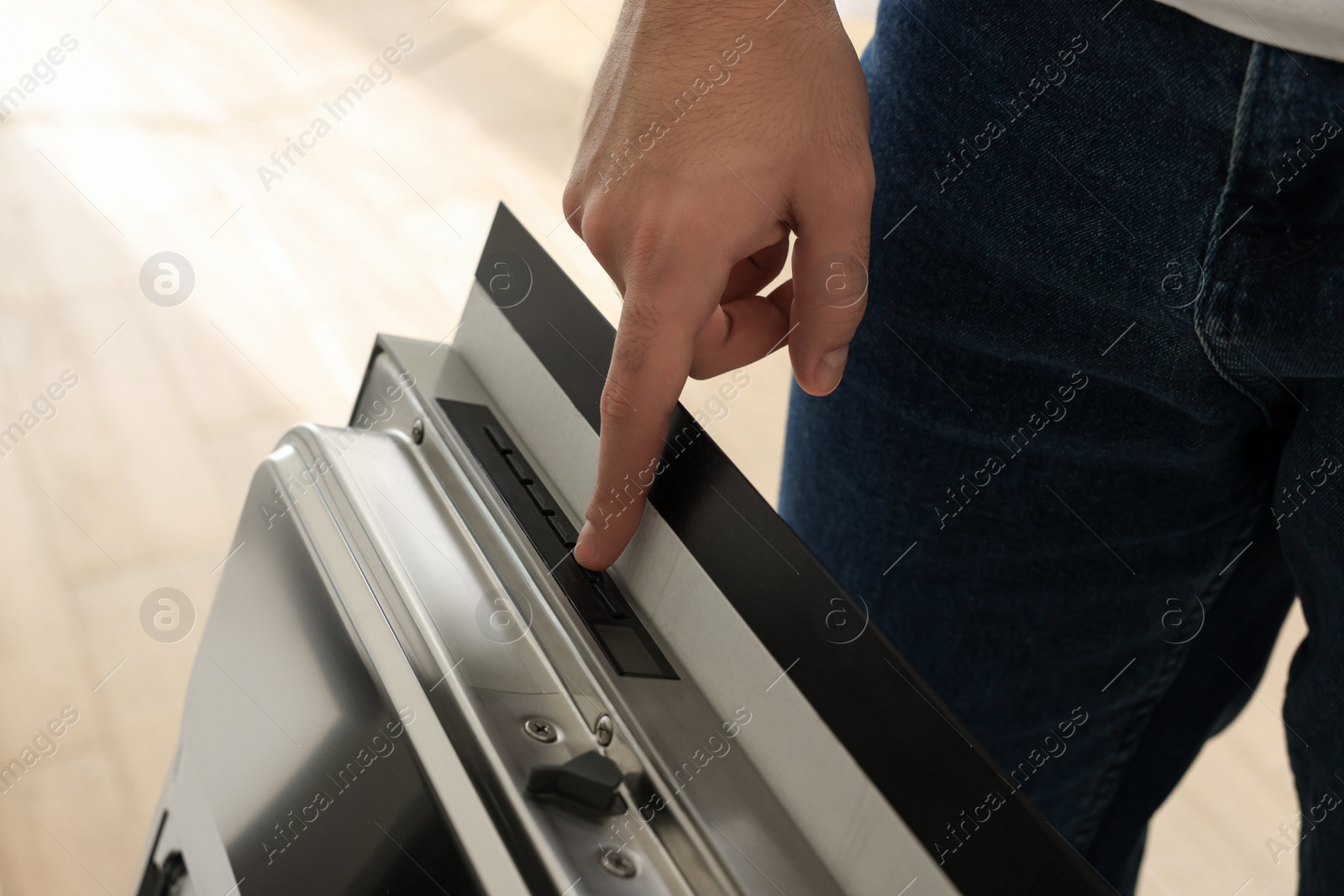 Photo of Man pushing button on dishwasher's door indoors, closeup