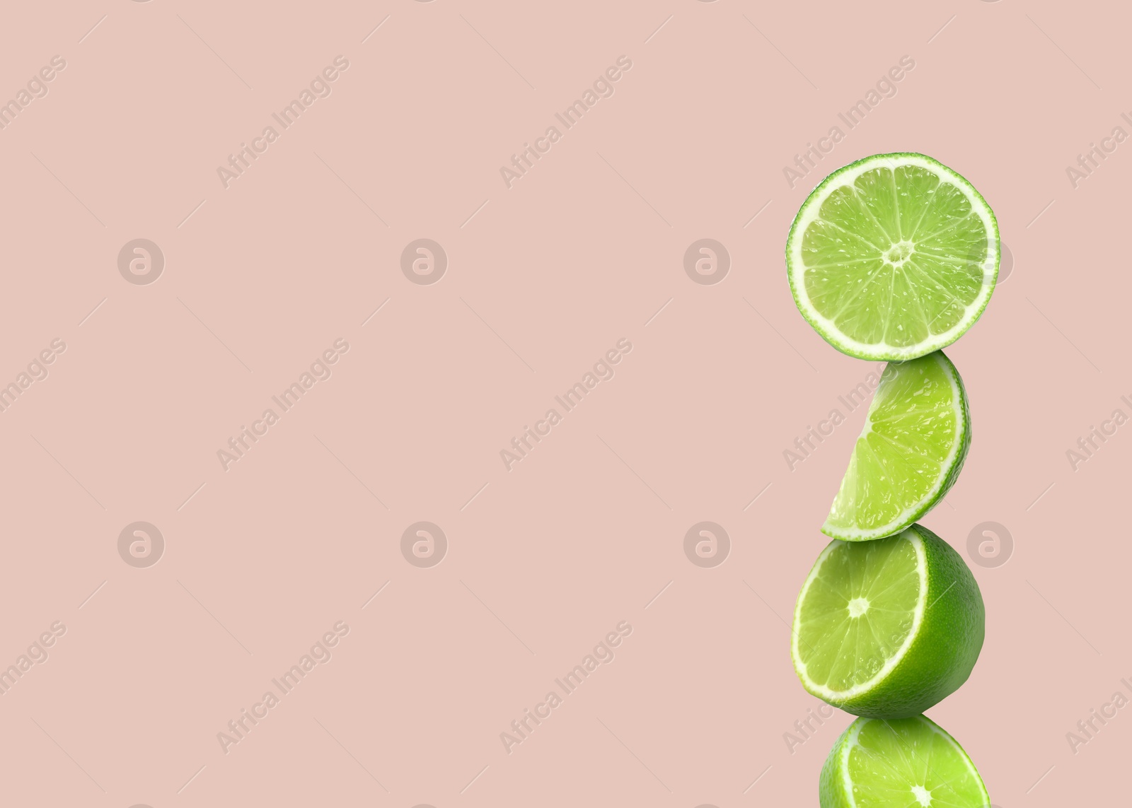 Image of Stacked cut limes on light pale pink background, space for text