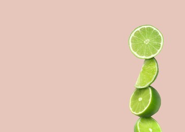 Image of Stacked cut limes on light pale pink background, space for text