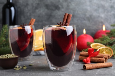Aromatic mulled wine and ingredients on grey table