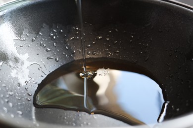 Photo of Pouring fresh oil into frying pan, closeup view