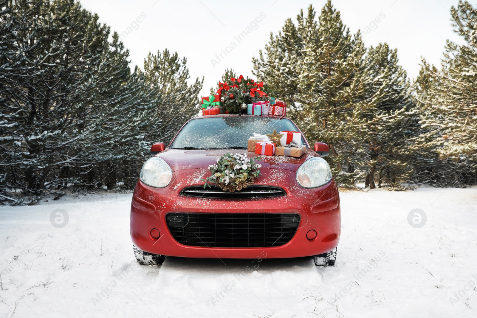 Photo of Car with Christmas tree, wreath and gifts in snowy forest on winter day