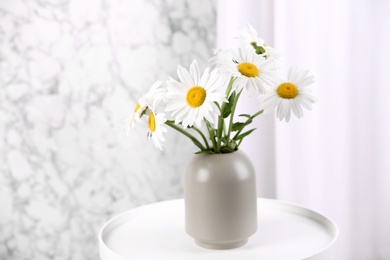 Beautiful tender chamomile flowers in vase on white table indoors