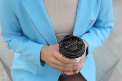 Photo of Coffee to go. Woman with paper cup of drink outdoors, closeup