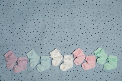 Photo of Many colorful baby socks on light blue fabric, flat lay. Space for text