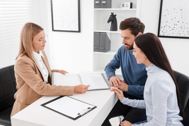 Photo of Real estate agent working with couple in office