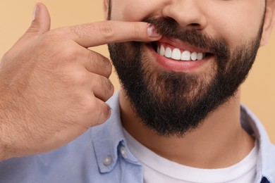 Photo of Man showing his clean teeth on beige background, closeup