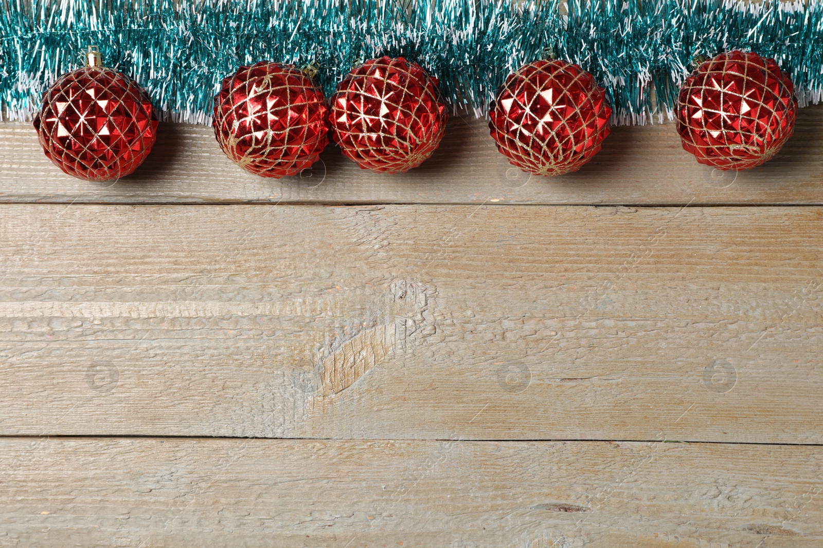 Photo of Bright tinsel and Christmas balls on wooden background, flat lay. Space for text