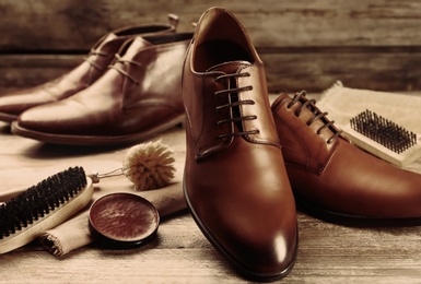 Image of Shoe care accessories and footwear on wooden table, closeup