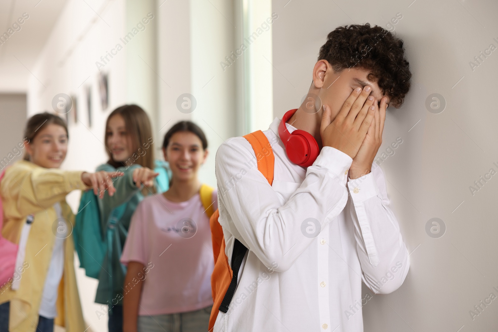 Photo of Teen problems. Group of students pointing at upset boy at school, selective focus