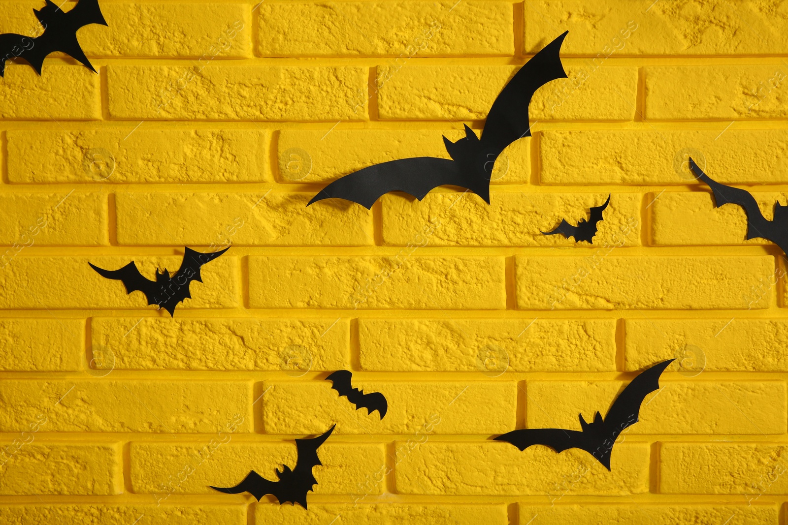 Photo of Yellow brick wall decorated for Halloween with paper bats