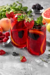 Photo of Delicious refreshing sangria with fresh fruits and berries on light grey table