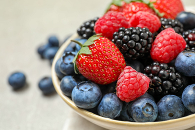 Photo of Mix of different fresh berries in bowl on light grey table, closeup