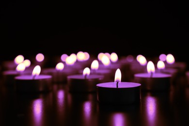 Image of Burning violet candle on black background, closeup. Funeral attributes