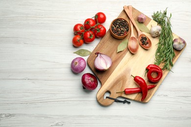 Cutting board and vegetables on white wooden table, flat lay with space for text. Cooking utensil