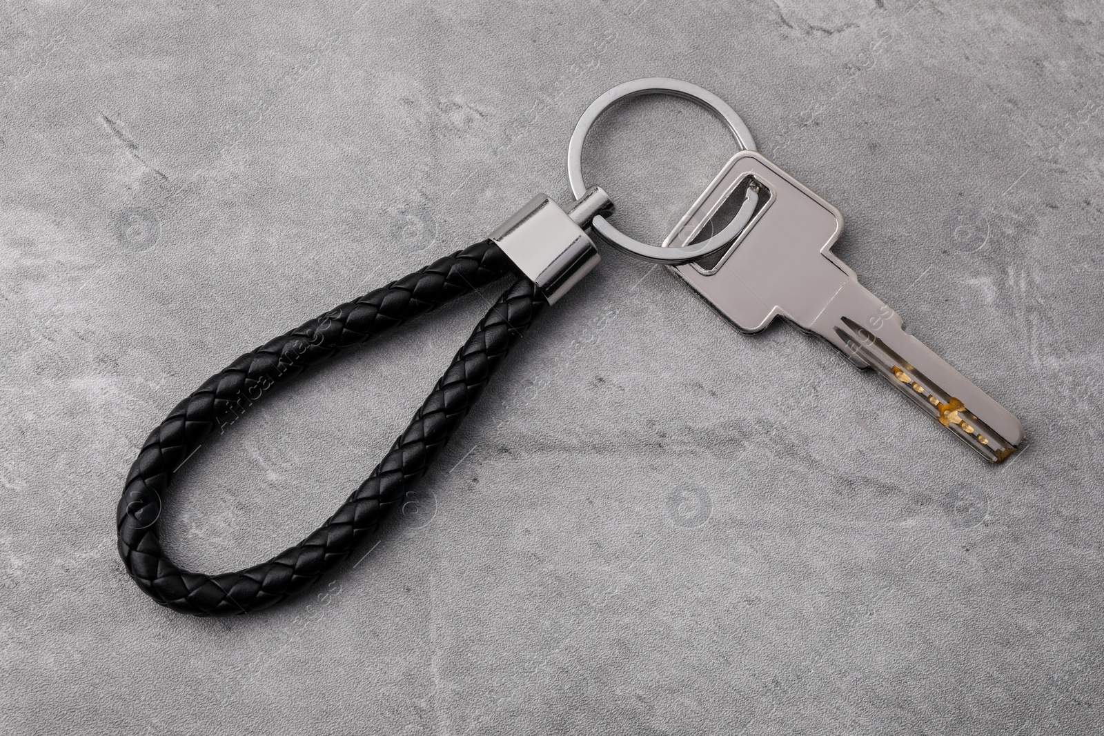 Photo of Key with black leather keychain on grey background, top view