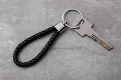 Photo of Key with black leather keychain on grey background, top view