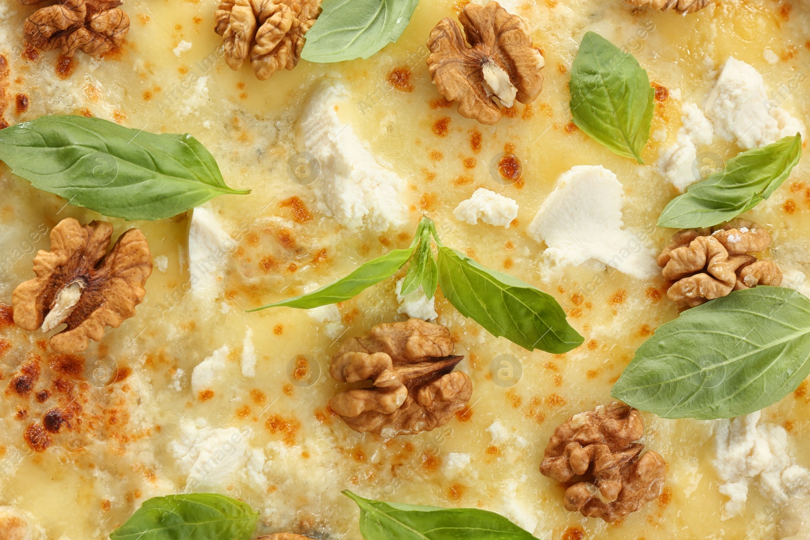 Photo of Delicious cheese pizza with walnuts and basil as background, closeup