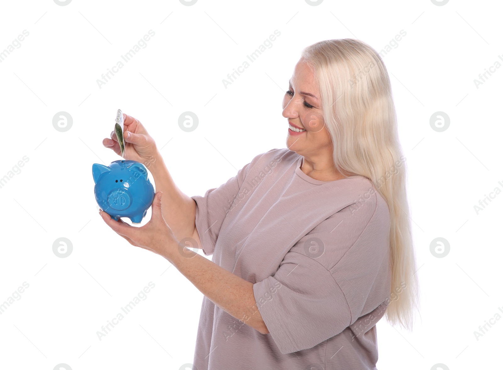 Photo of Mature woman putting money into piggy bank on white background