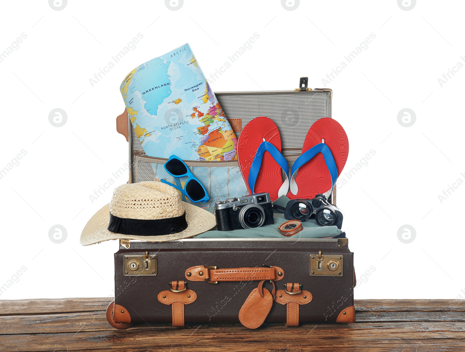 Photo of Open vintage suitcase with clothes packed for summer vacation on wooden table against white background