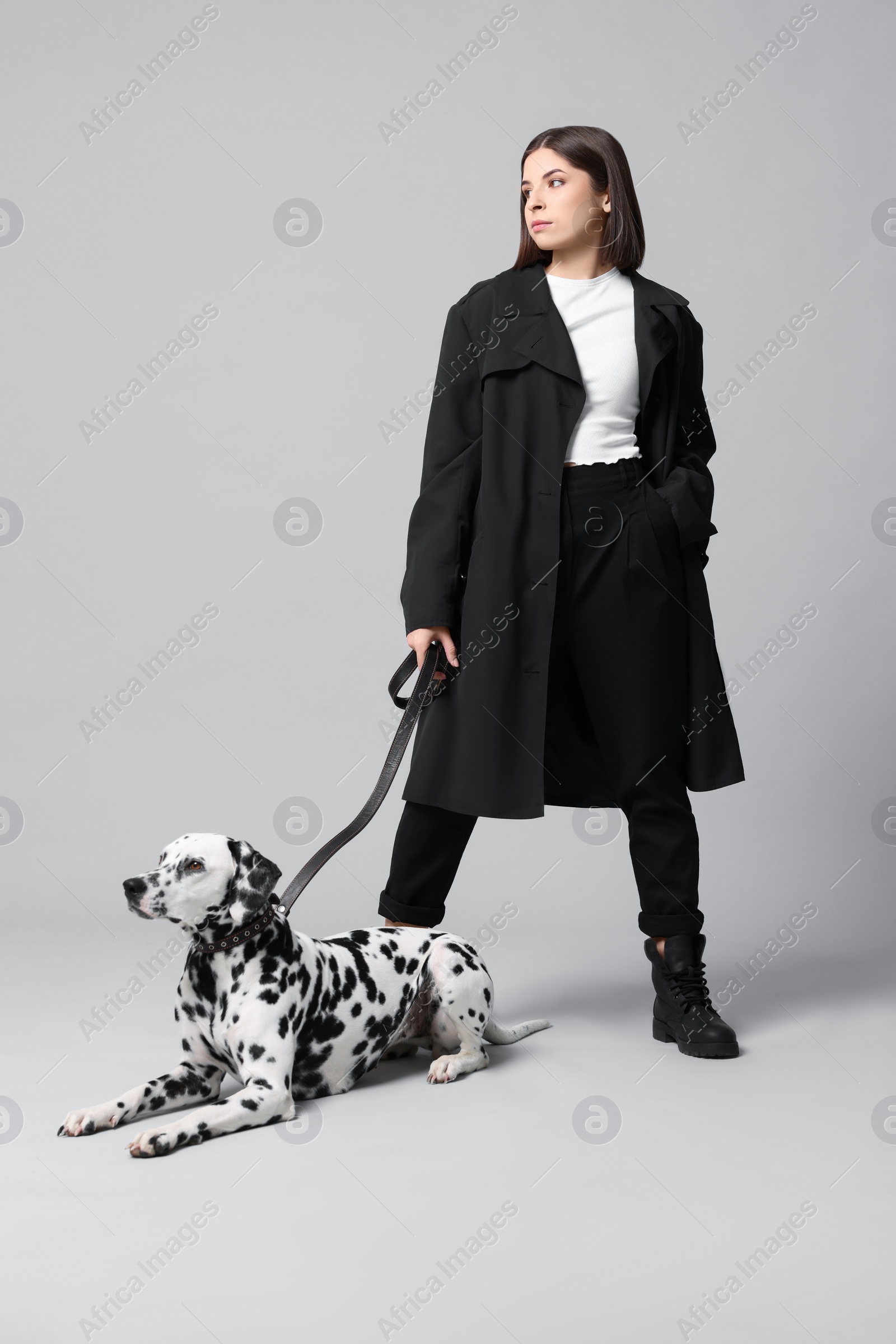 Photo of Beautiful young woman with her adorable Dalmatian dog on light grey background. Lovely pet