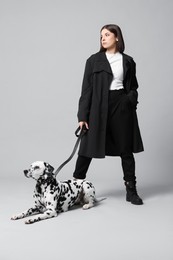 Photo of Beautiful young woman with her adorable Dalmatian dog on light grey background. Lovely pet