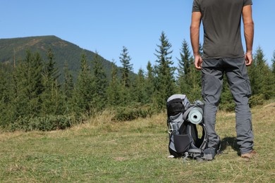 Photo of Man with backpack and sleeping mat in mountains, closeup. Space for text