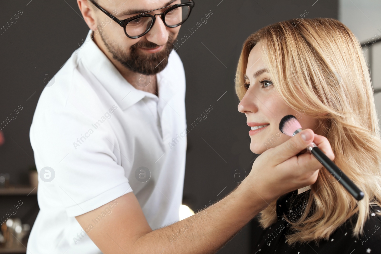 Photo of Professional makeup artist working with client in dressing room