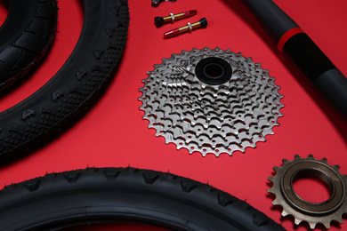 Photo of Set of different bicycle tools and parts on red background, closeup
