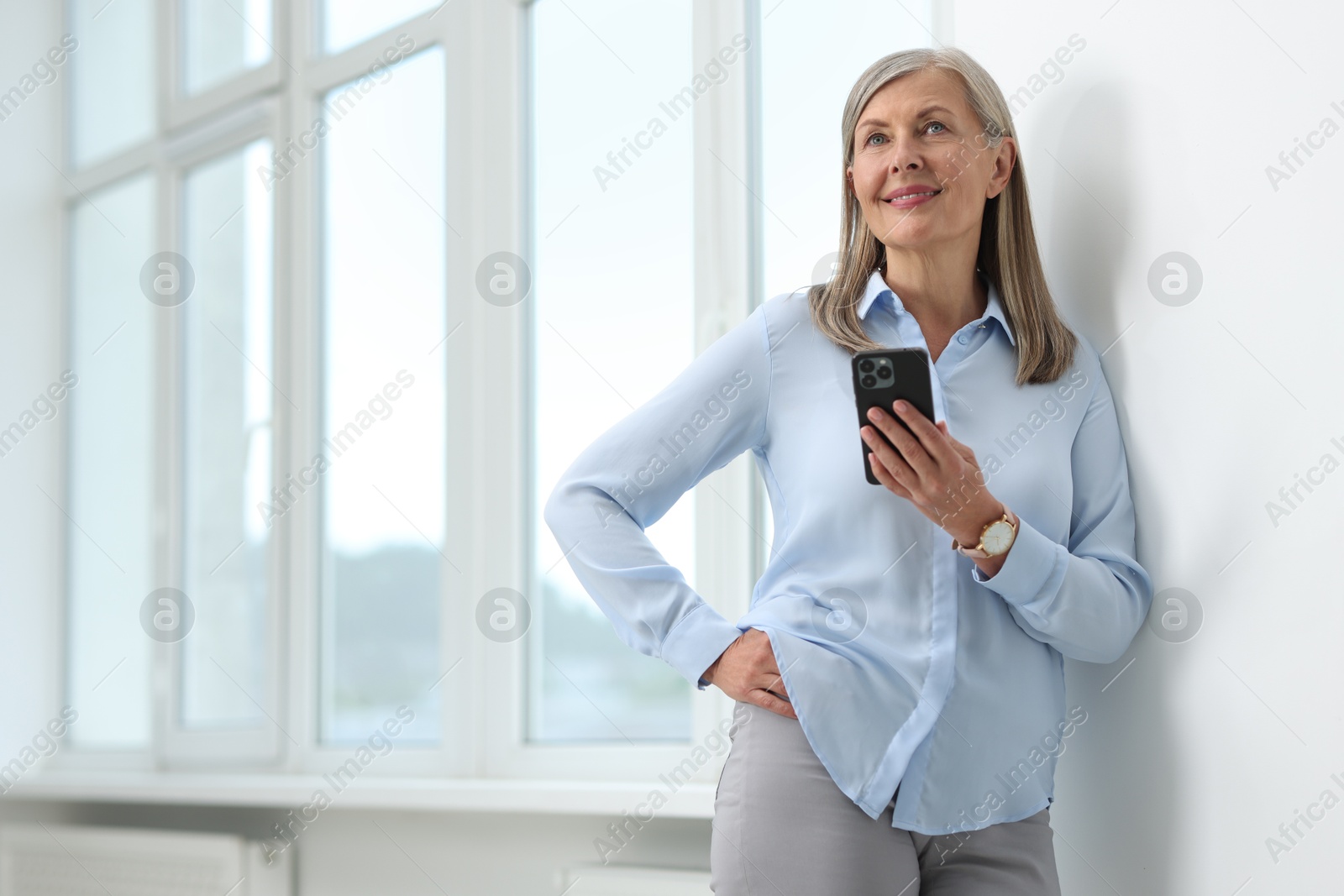 Photo of Senior woman using mobile phone at home, space for text