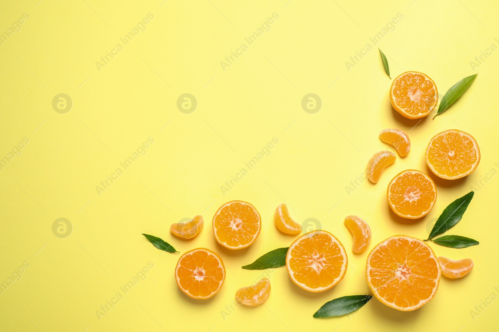 Photo of Flat lay composition with fresh ripe tangerines and leaves on light yellow background, space for text. Citrus fruit