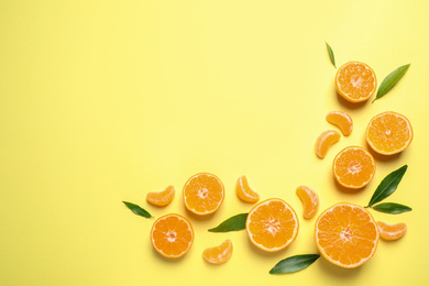 Flat lay composition with fresh ripe tangerines and leaves on light yellow background, space for text. Citrus fruit