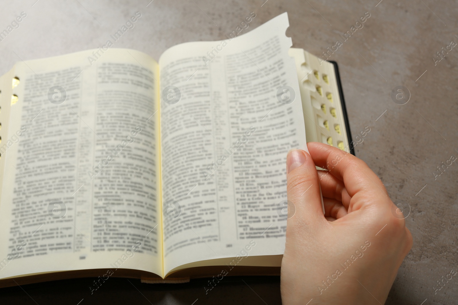 Photo of Above view of woman reading Bible at light grey table, closeup