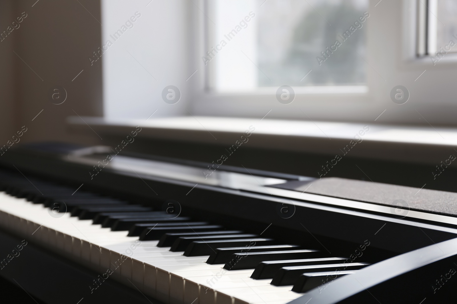 Photo of Modern piano near window in room, closeup