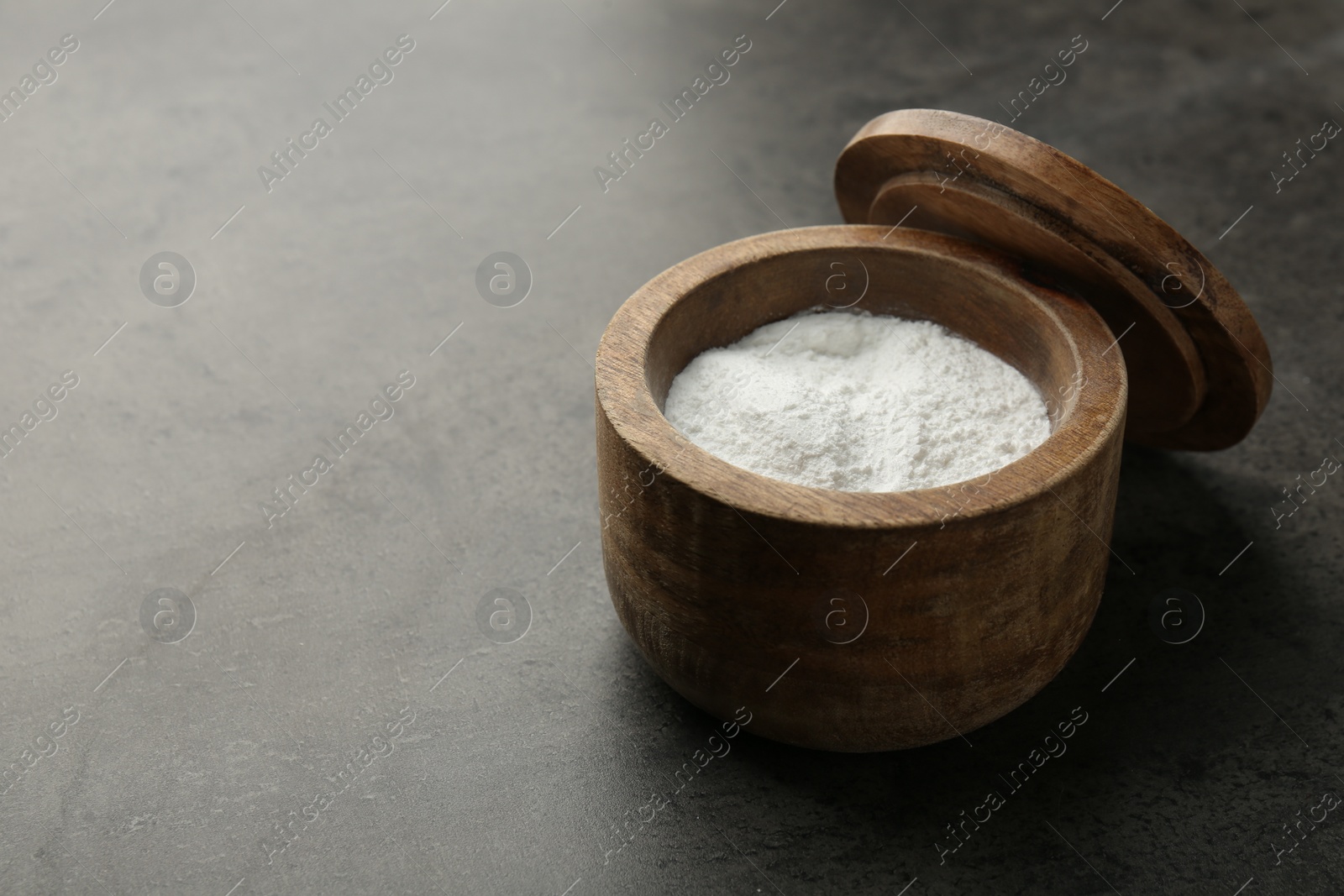 Photo of Baking powder in bowl on grey textured table, space for text