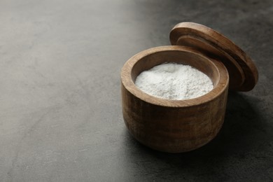 Photo of Baking powder in bowl on grey textured table, space for text