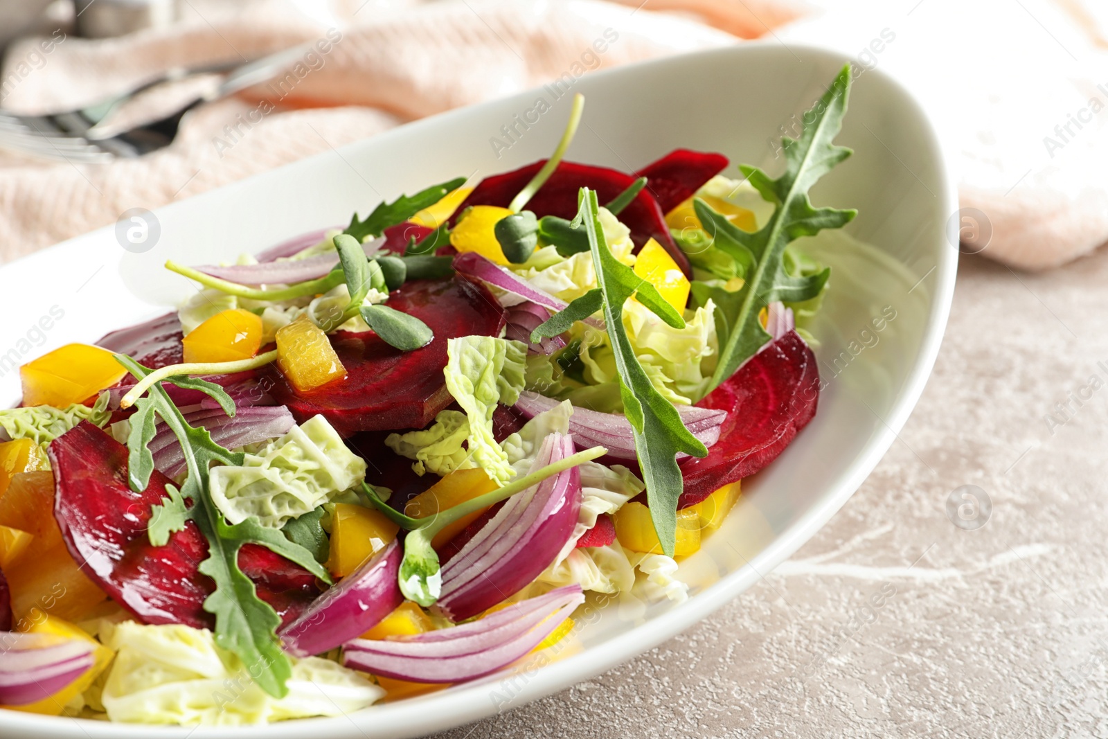 Photo of Bowl with tasty beets salad on gray table