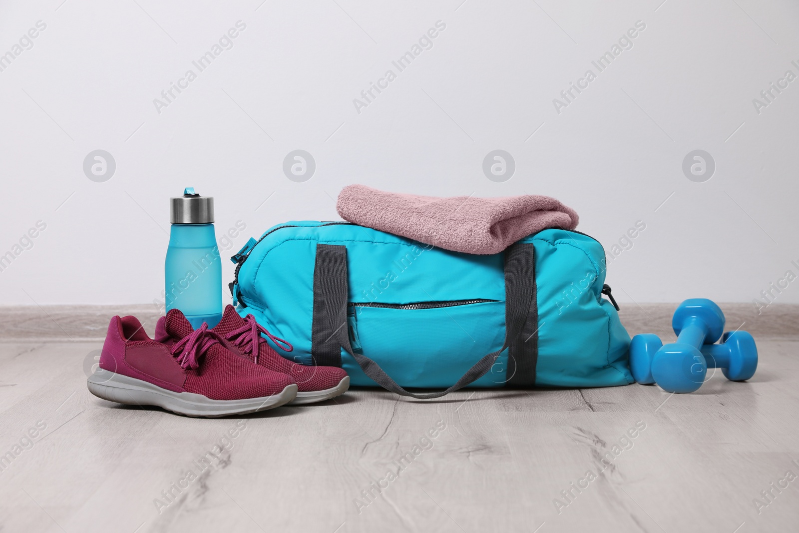 Photo of Bag with different sports equipment on wooden floor indoors