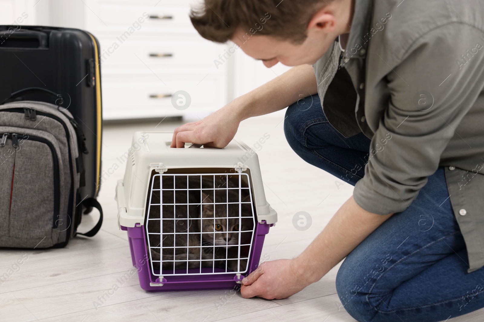 Photo of Travel with pet. Man closing carrier with cat indoors