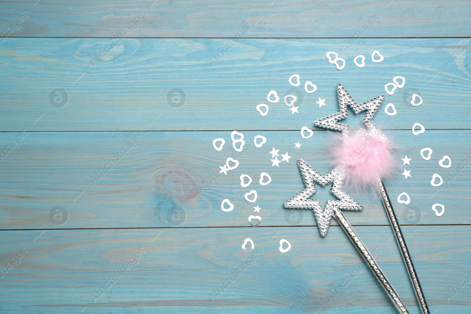 Photo of Beautiful silver magic wands and confetti on turquoise wooden table, flat lay. Space for text