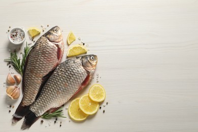 Photo of Fresh raw crucian carps and ingredients on light wooden table, flat lay with space for text. River fish