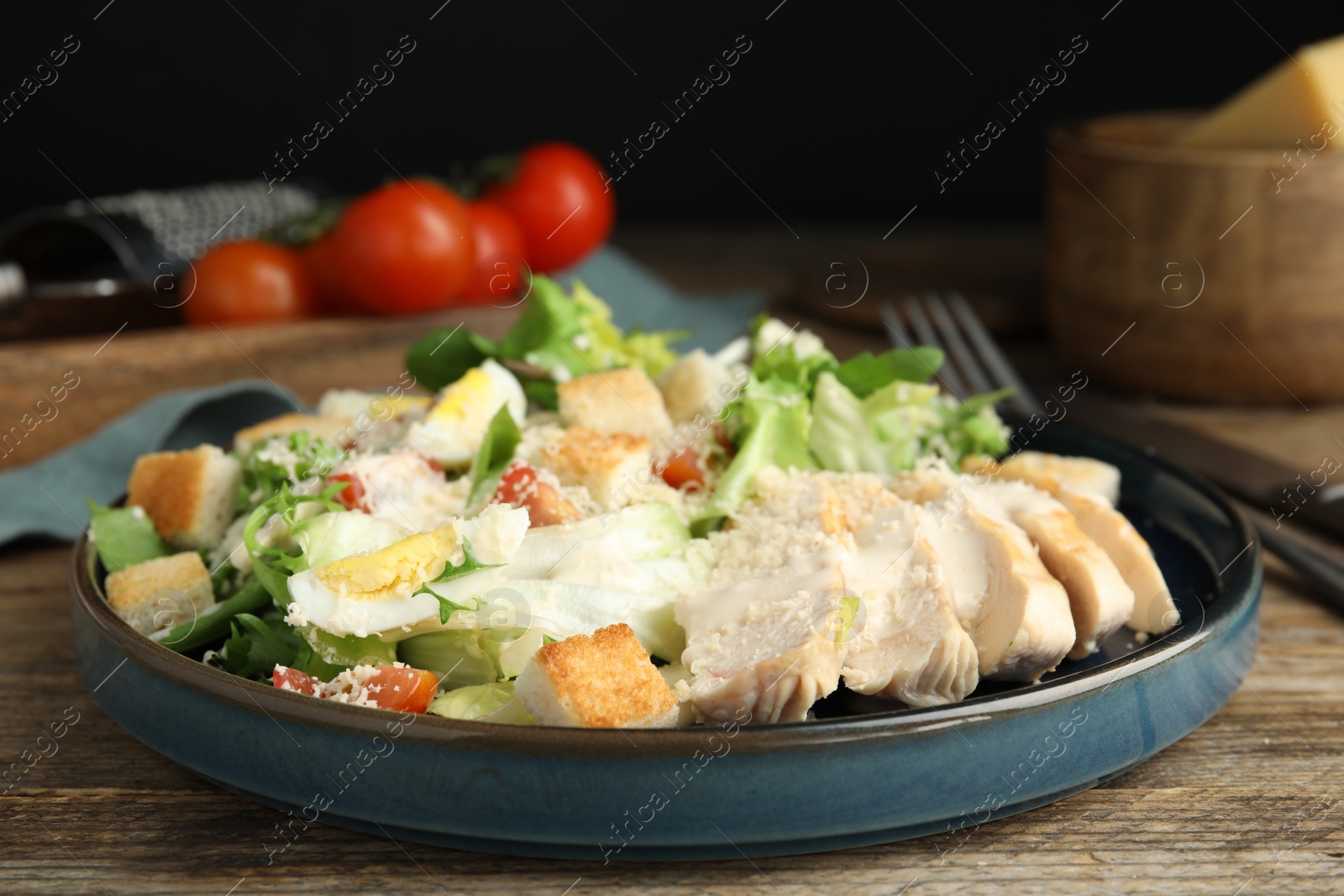 Photo of Delicious Caesar salad in bowl on wooden table