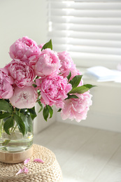 Photo of Bouquet of beautiful peonies on pouf indoors
